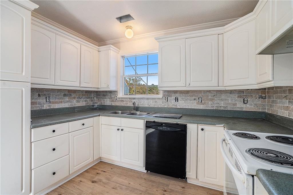 2000 Sage Court Loganville, GA 30052 - Photo 29 of 35 a kitchen with white cabinets and a stove with wooden floor