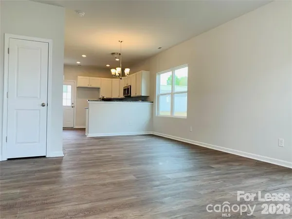 a view of a kitchen with a fridge and wooden floor