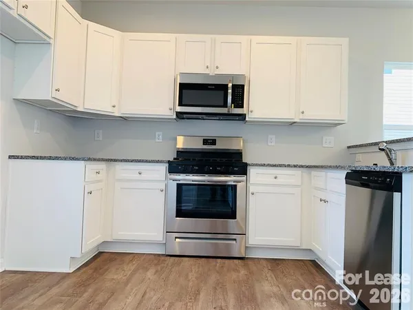 a kitchen with granite countertop white cabinets and stainless steel appliances