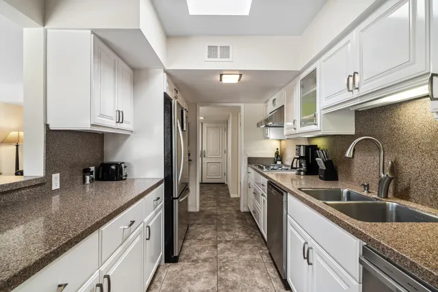 a kitchen with stainless steel appliances granite countertop a sink stove refrigerator and cabinets