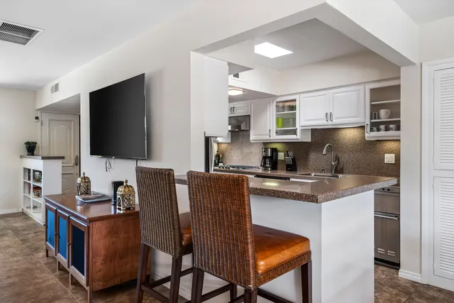a kitchen with stainless steel appliances granite countertop a table chairs sink and cabinets