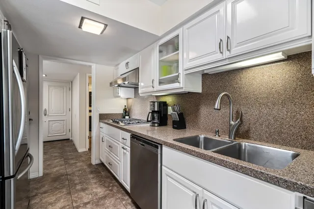 a kitchen with stainless steel appliances granite countertop a sink and a refrigerator