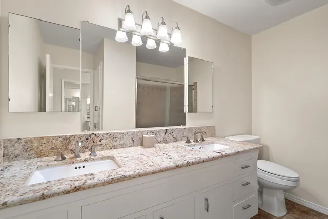 a bathroom with a granite countertop double vanity sink and a mirror