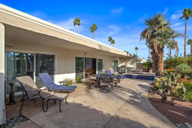 a view of a patio with table and chairs potted plants and palm tree