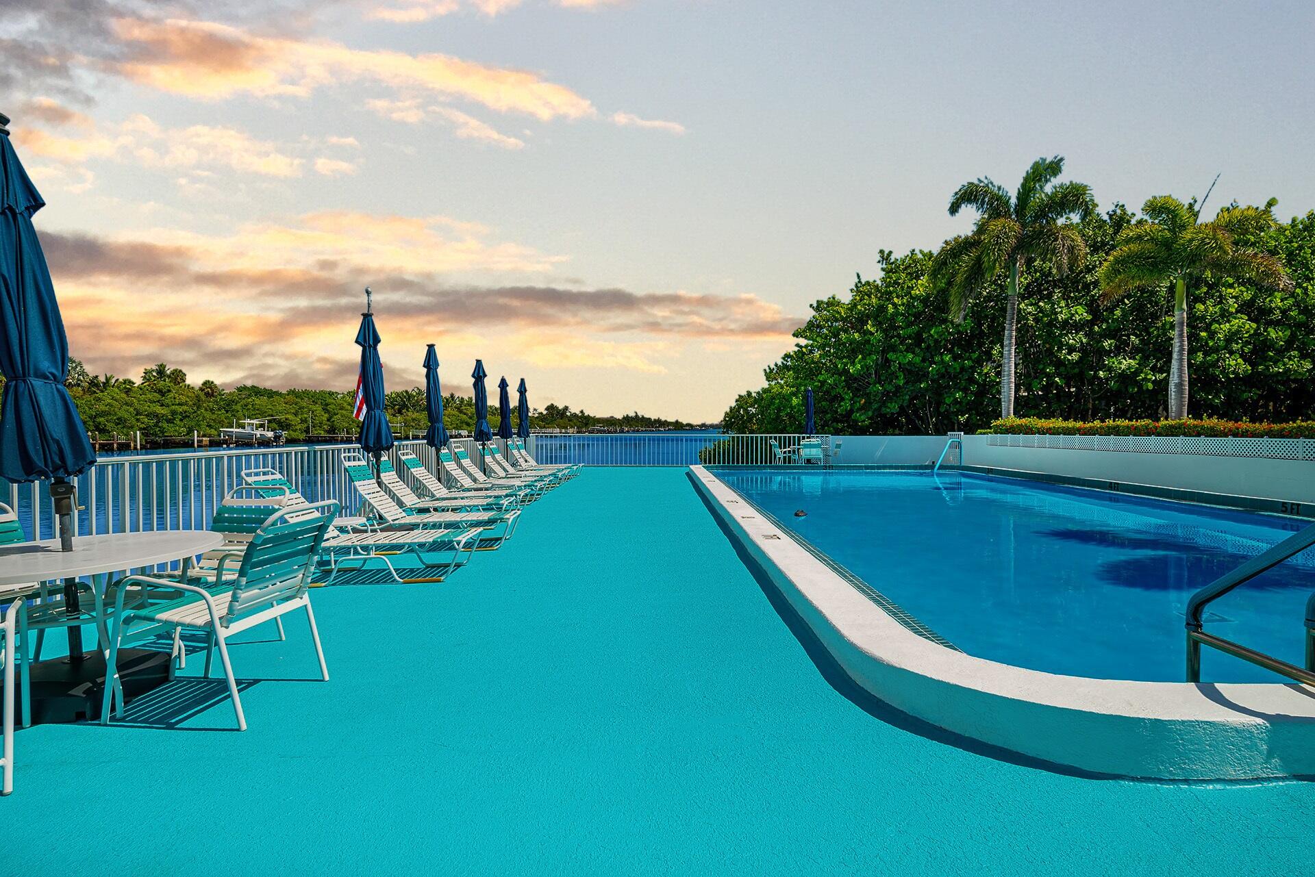 4001 South Ocean Boulevard, Unit 115 South Palm Beach, FL 33480 - Photo 1 of 25 a view of a swimming pool with lawn chairs with wooden fence