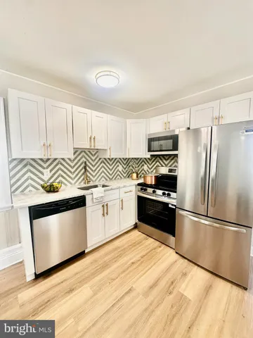 a kitchen with granite countertop a refrigerator oven a sink and cabinets