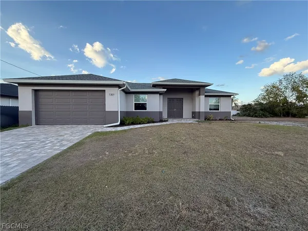 a front view of house with yard and trees in the background