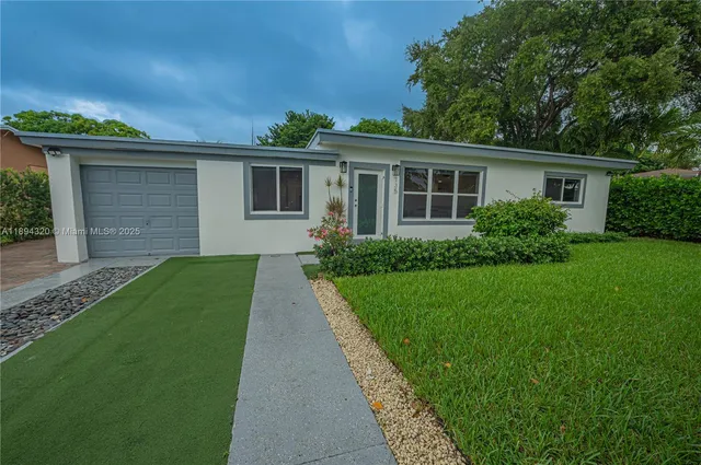 a front view of a house with a yard and potted plants
