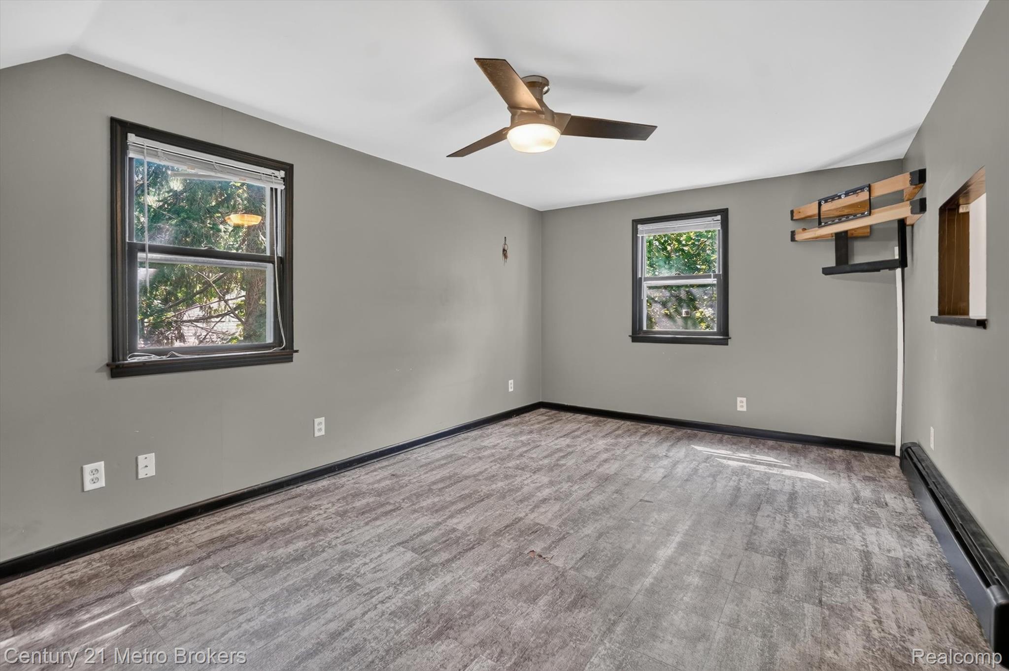 4575 Brockway Road Saginaw, MI 48638 - Photo 26 of 44 Spacious room featuring wood-finish flooring, two windows with dark trim, a ceiling fan, and a wall-mounted bracket