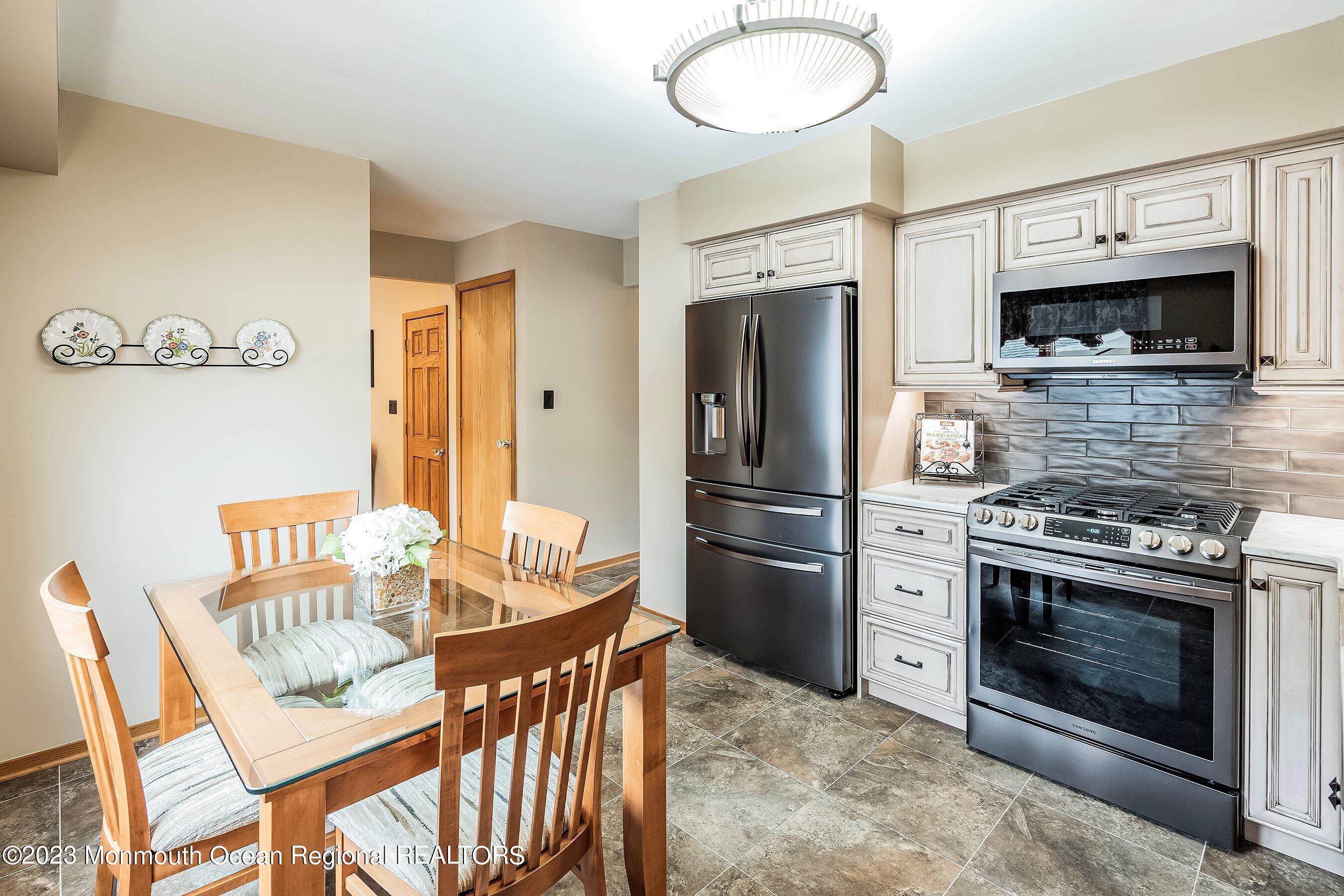 1 Hearth Court Howell, NJ 07731 - Photo 9 of 23 a kitchen with stainless steel appliances a stove a microwave a dining table and chairs