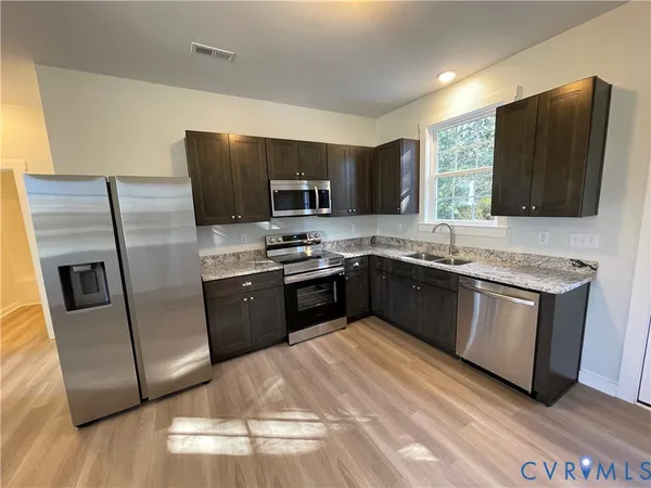 a kitchen with stainless steel appliances granite countertop a refrigerator stove a sink and a microwave