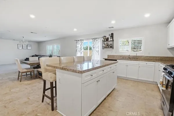 a kitchen with stainless steel appliances granite countertop a stove a sink a refrigerator with a dining table and chairs