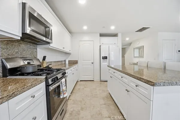 a kitchen with granite countertop white cabinets sink and stainless steel appliances