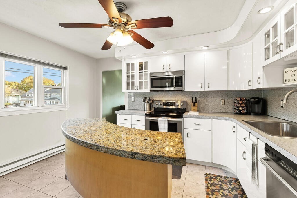 23 Appleton Street Saugus, MA 01906 - Photo 14 of 30 a kitchen with kitchen island granite countertop a sink stainless steel appliances and white cabinets
