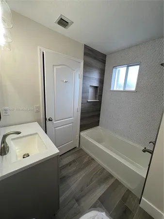 a bathroom with a tub sink and mirror