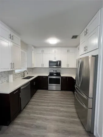 a large kitchen with cabinets stainless steel appliances and a sink