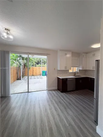 a living room with a large window wooden floor and glass door