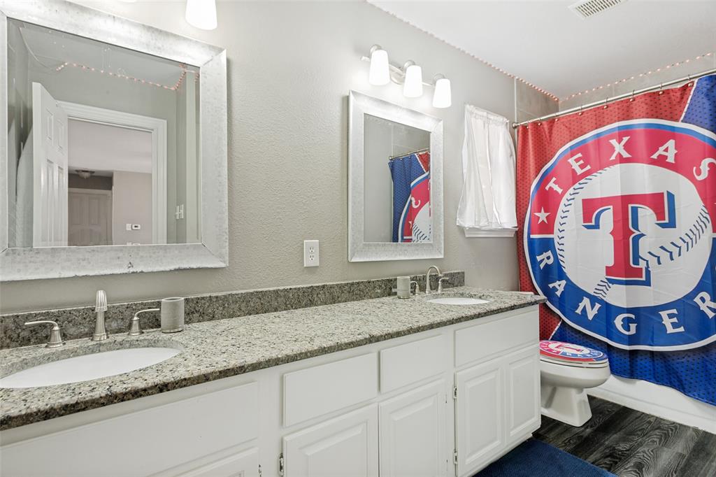1228 Concho Drive Benbrook, TX 76126 - Photo 28 of 39 Dual vanity featuring white cabinetry, undermount sinks, and a stone-finish countertop