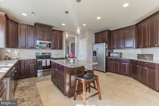 a kitchen with kitchen island granite countertop wooden cabinets and stainless steel appliances