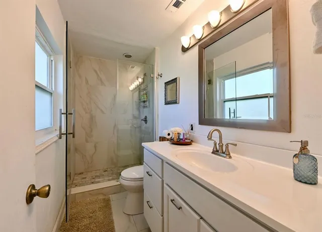 a bathroom with a sink a toilet a mirror and shower