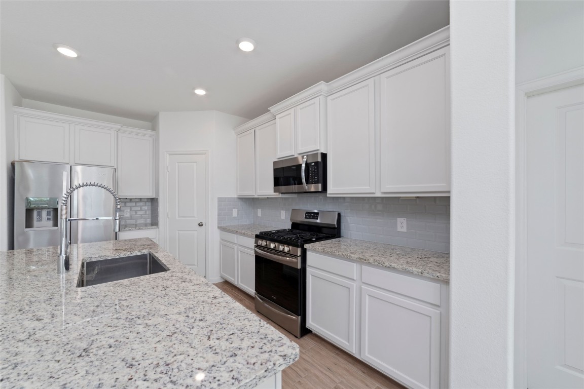 11023 Abendstern Road Tomball, TX 77375 - Photo 11 of 26 a kitchen with granite countertop white cabinets and stainless steel appliances