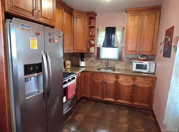 a kitchen with stainless steel appliances granite countertop a refrigerator a stove a sink and a microwave