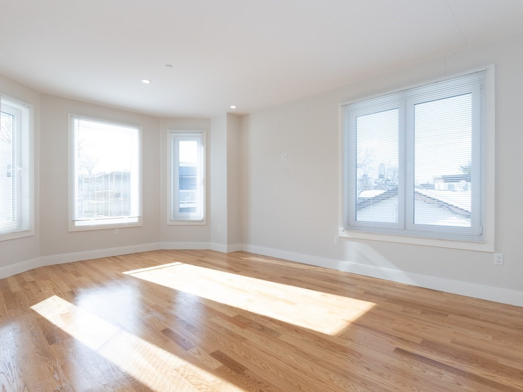 9 Tovar Street, Unit 2 Boston, MA 02122 - Photo 3 of 22 an empty room with wooden floor and windows