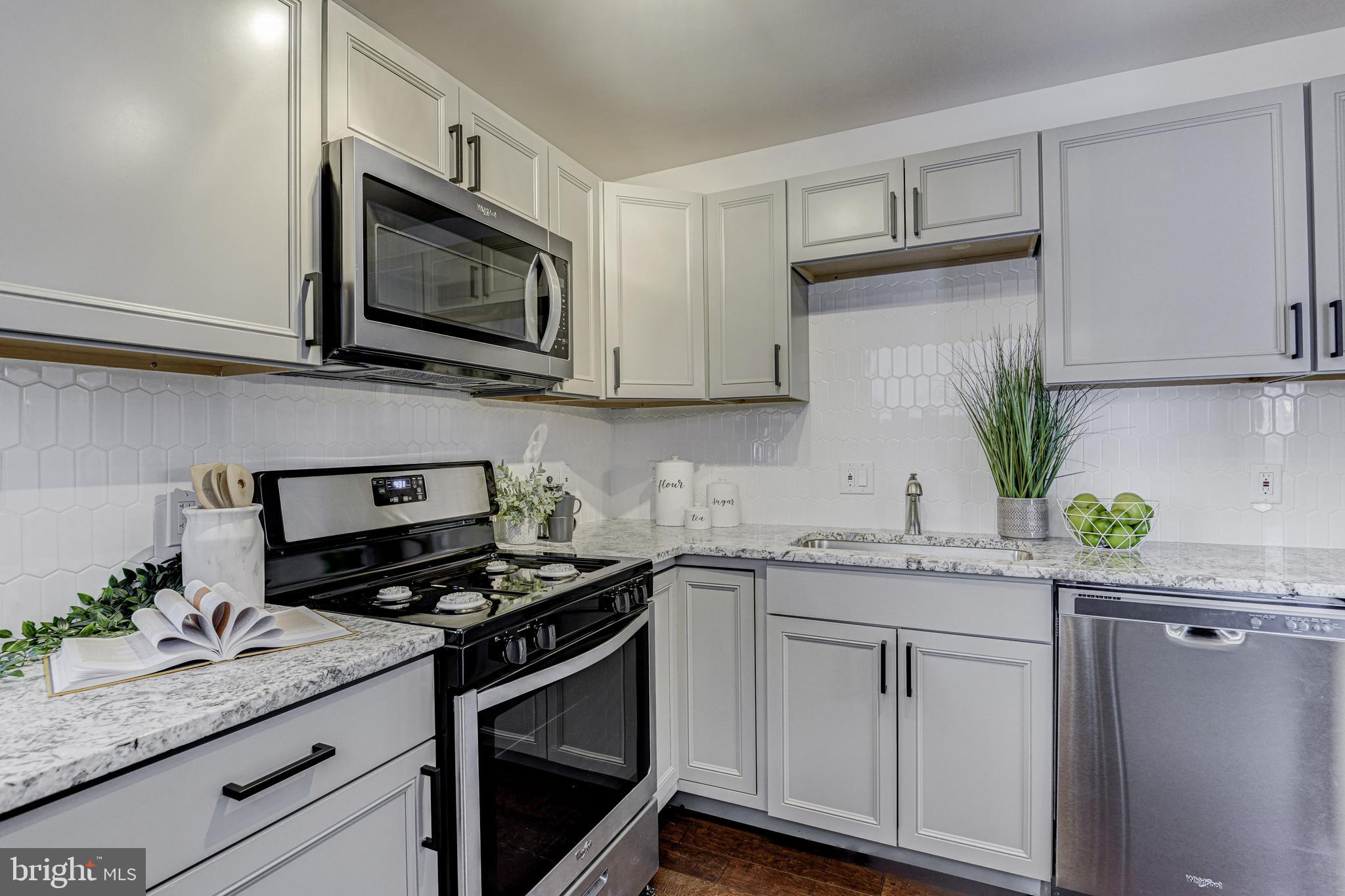 a kitchen with granite countertop white cabinets appliances and a potted plant