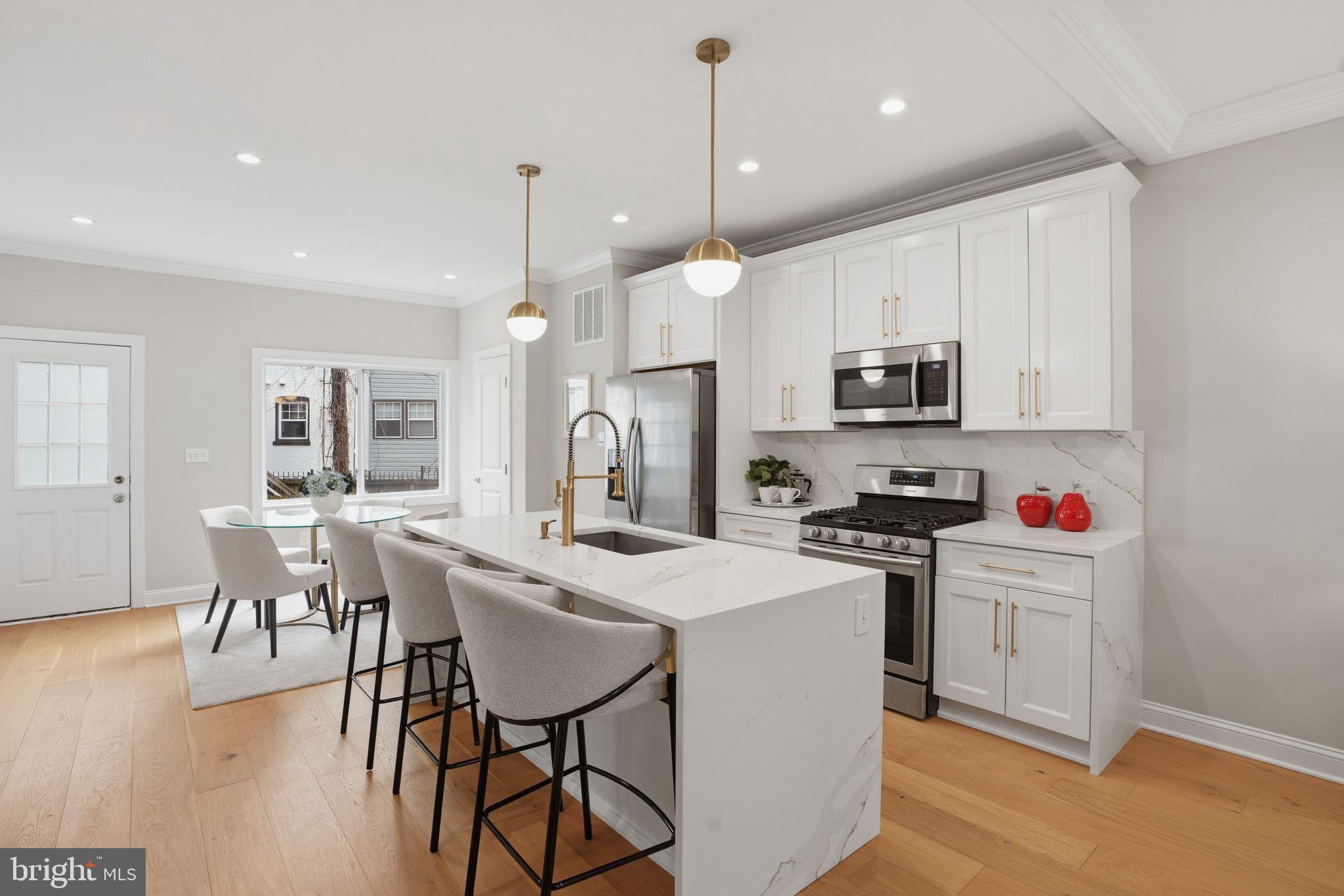 1208 Shepherd Street Northwest Washington, DC 20011 - Photo 6 of 27 a kitchen with stainless steel appliances kitchen island granite countertop a stove a sink a microwave a dining table and chairs with wooden floor