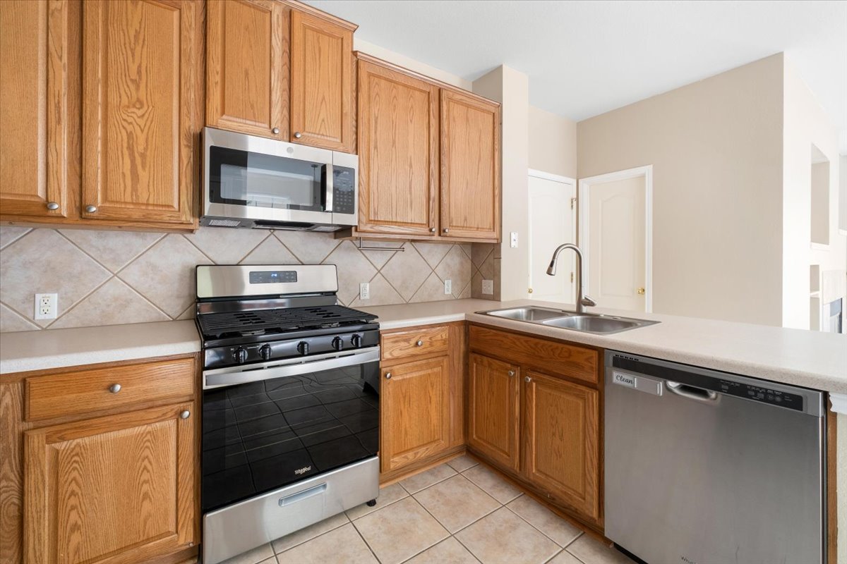 11000 Anderson Mill Road, Unit 11 Austin, TX 78750 - Photo 8 of 34 A functional kitchen features stainless steel appliances, rich wooden cabinetry, and durable tile flooring.
