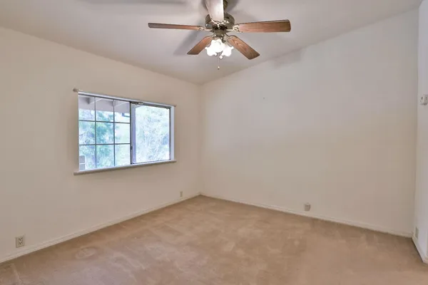 an empty room with closet and a chandelier fan