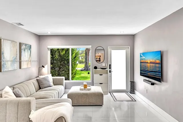 a living room with furniture tv floor to ceiling window and a flat screen tv