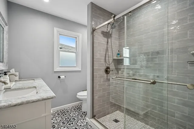 a bathroom with a granite countertop sink a toilet and shower