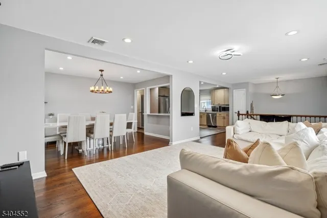 a living room with furniture kitchen view and a wooden floor