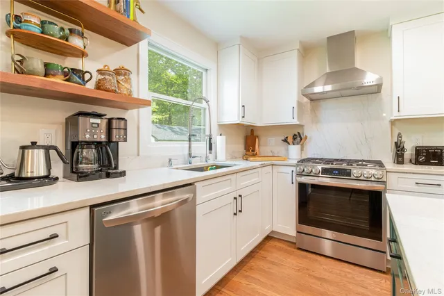 a kitchen with stainless steel appliances granite countertop a sink a stove and a wooden floors