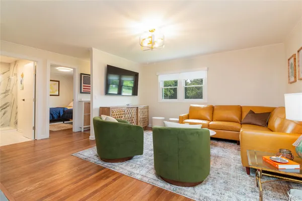 a living room with furniture a flat screen tv and wooden floor