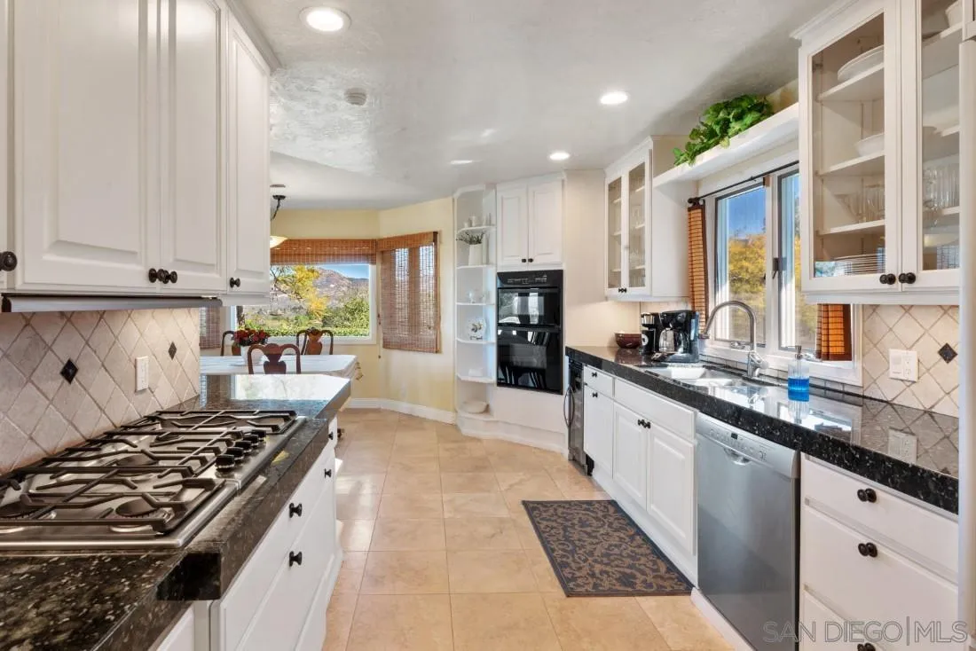 16033 Stoney Acres Road Poway, CA 92064 - Photo 23 of 60 a large white kitchen with stainless steel appliances granite countertop a stove and a sink