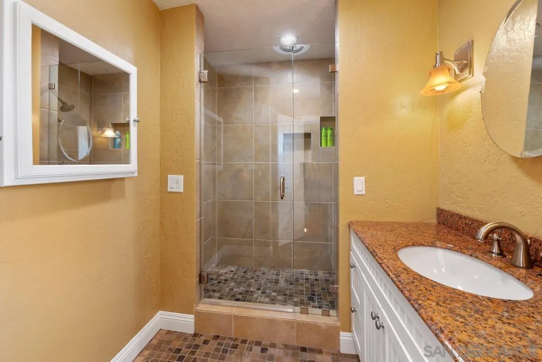 16033 Stoney Acres Road Poway, CA 92064 - Photo 26 of 60 a bathroom with a granite countertop sink a mirror and a shower