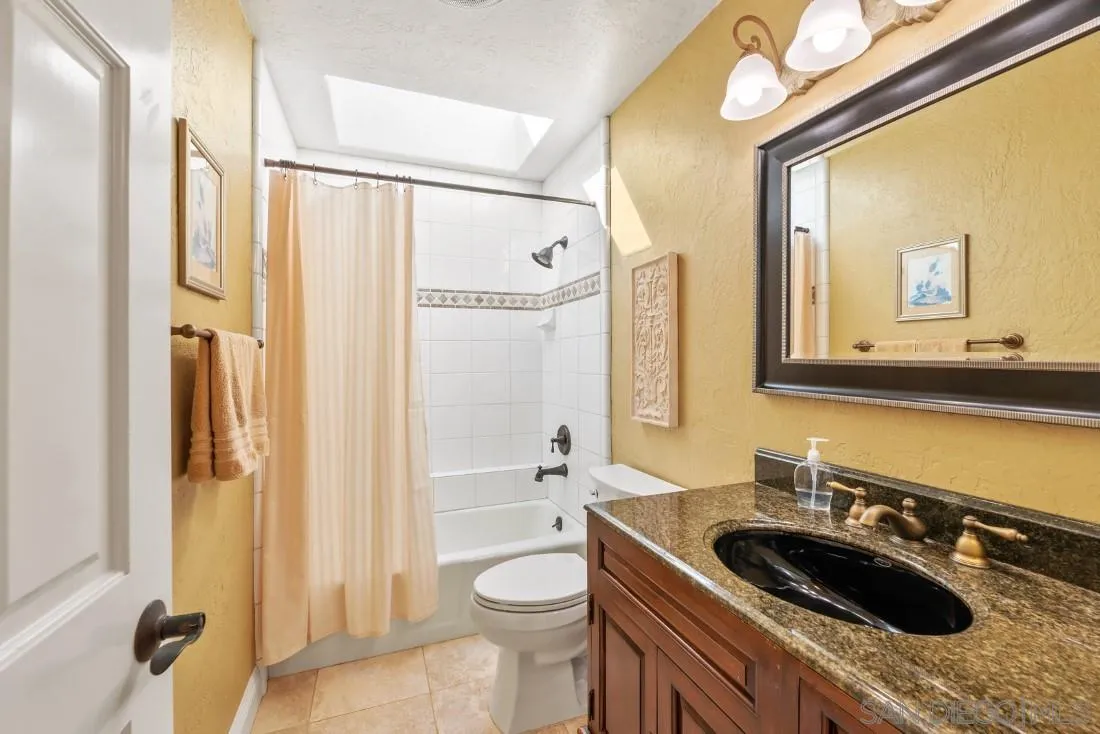 16033 Stoney Acres Road Poway, CA 92064 - Photo 31 of 60 a bathroom with a granite countertop sink a toilet a mirror and shower
