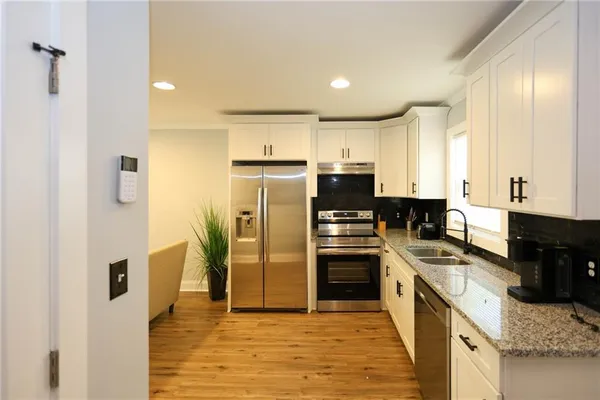 a kitchen with stainless steel appliances granite countertop a refrigerator a stove and a sink