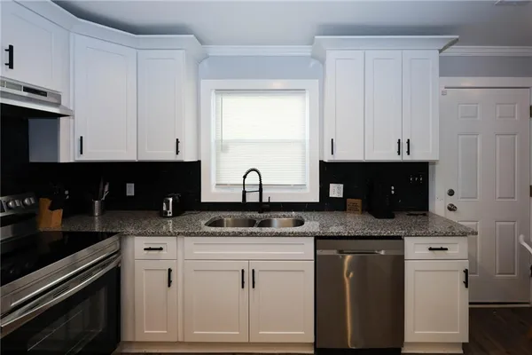 a kitchen with granite countertop white cabinets and black appliances