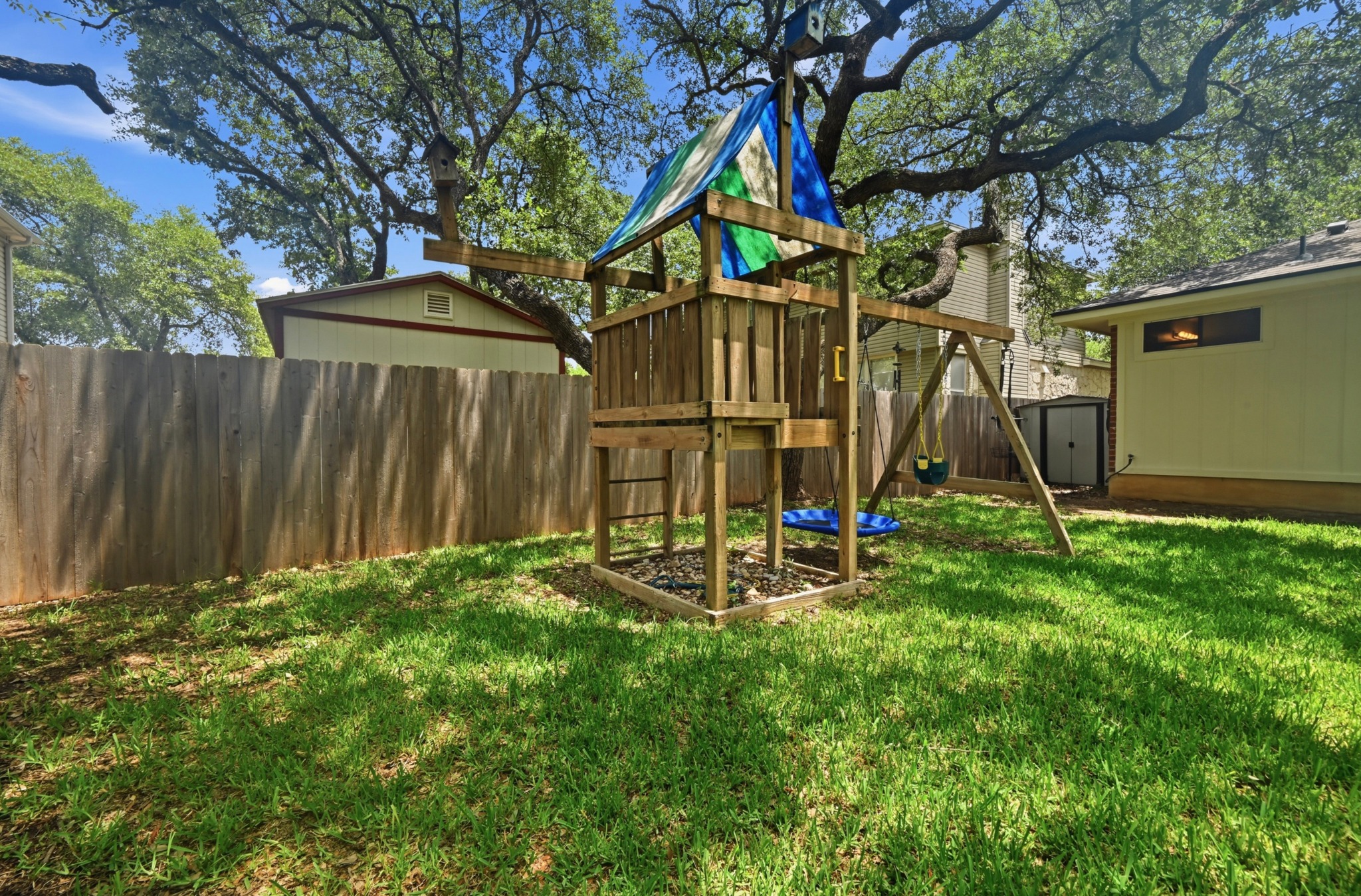 1409 Knoll Ridge Drive Cedar Park, TX 78613 - Photo 28 of 30 A private, fenced backyard offers a wooden playset under mature trees for outdoor enjoyment.