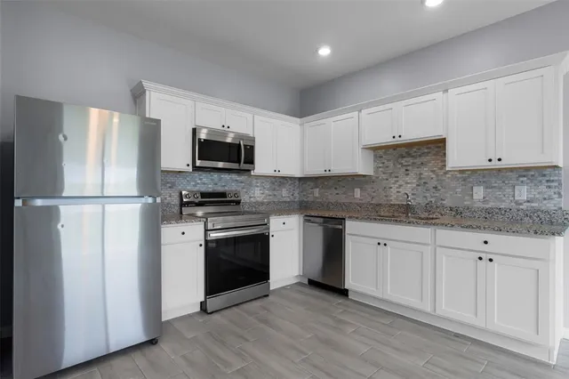 a kitchen with granite countertop a refrigerator stove and sink