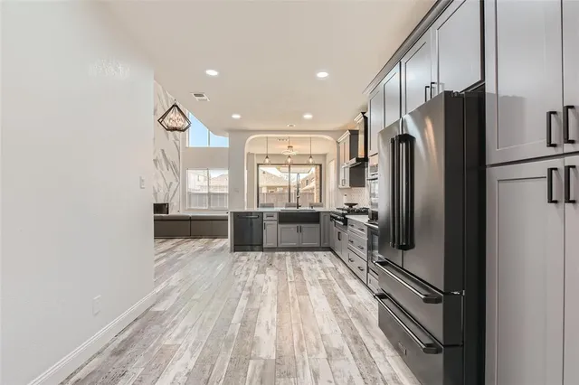 a large kitchen with a lot of counter space a refrigerator and windows