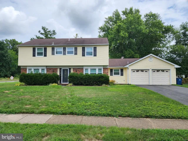 a view of a house next to a yard with plants and trees