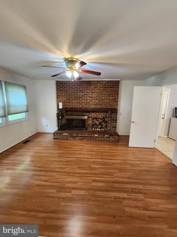 a view of empty room with wooden floor and fireplace