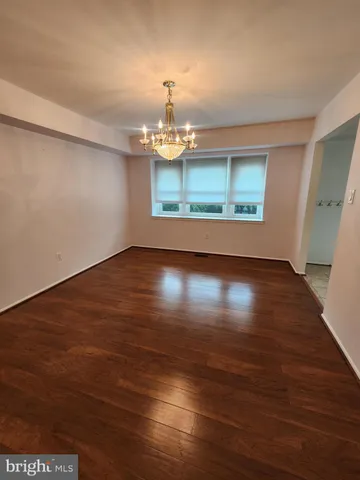 an empty room with wooden floor chandelier and windows