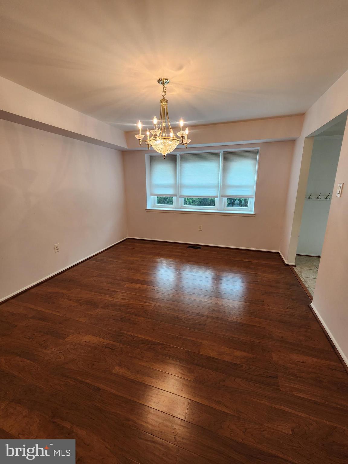 13171 Morning Spring Lane Fairfax, VA 22033 - Photo 9 of 34 an empty room with wooden floor chandelier and windows