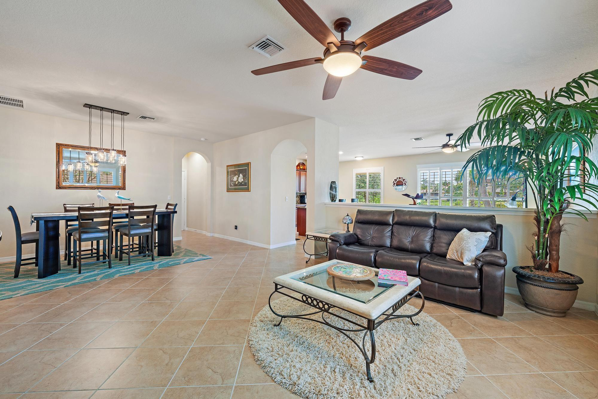 198 Umbrella Place Jupiter, FL 33458 - Photo 5 of 39 a living room with furniture a chandelier and a dining table with potted plants