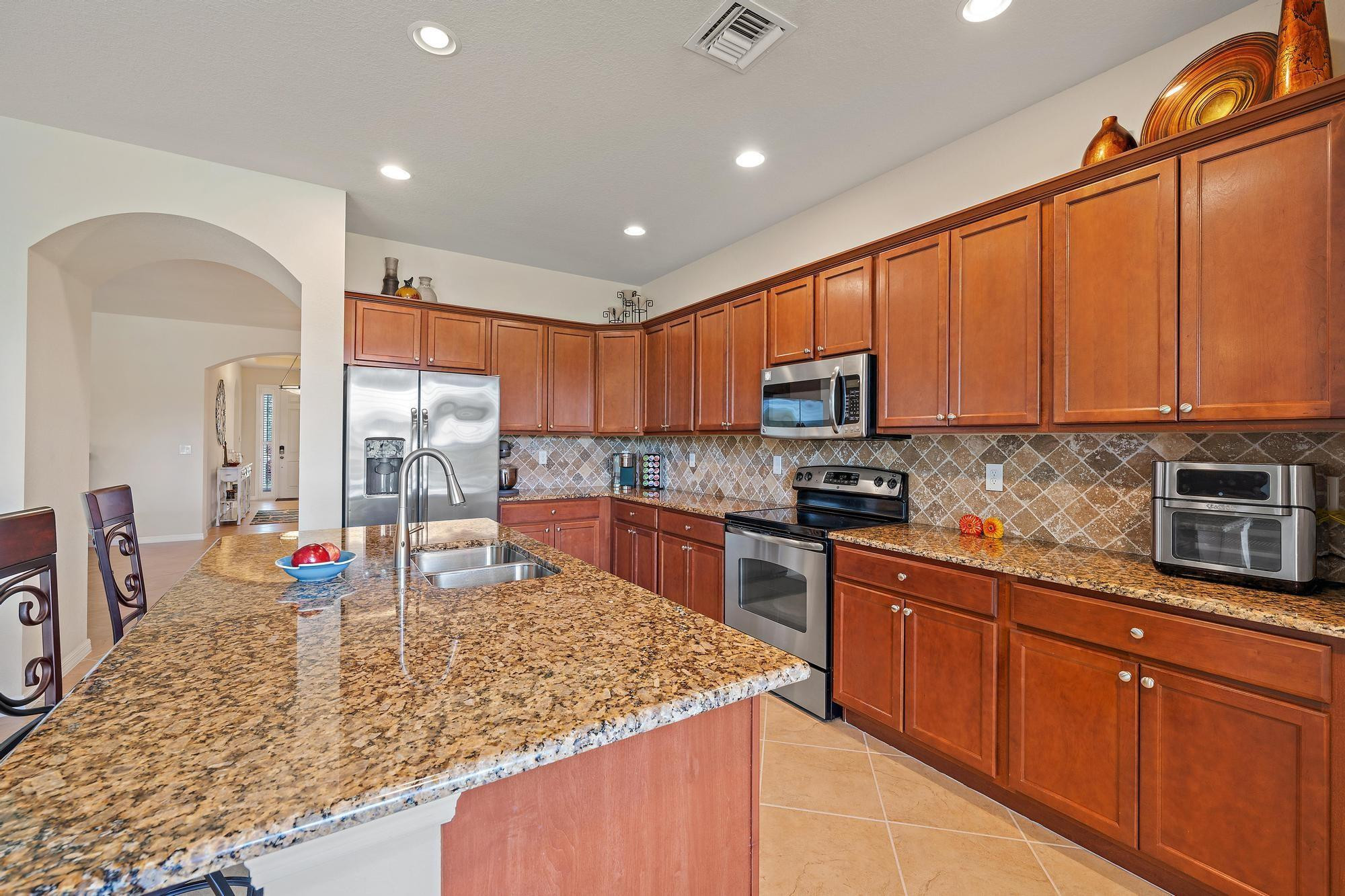 198 Umbrella Place Jupiter, FL 33458 - Photo 9 of 39 a kitchen with stainless steel appliances granite countertop sink microwave and window